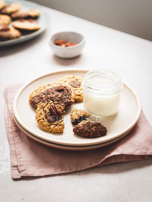 De cima de biscoitos de noz doces e vidro de leite servido na chapa na mesa — Fotografia de Stock
