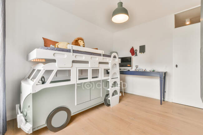Interno di spaziosa camera da letto per bambini con letto a forma di auto e pareti bianche in appartamento moderno durante il giorno — Foto stock