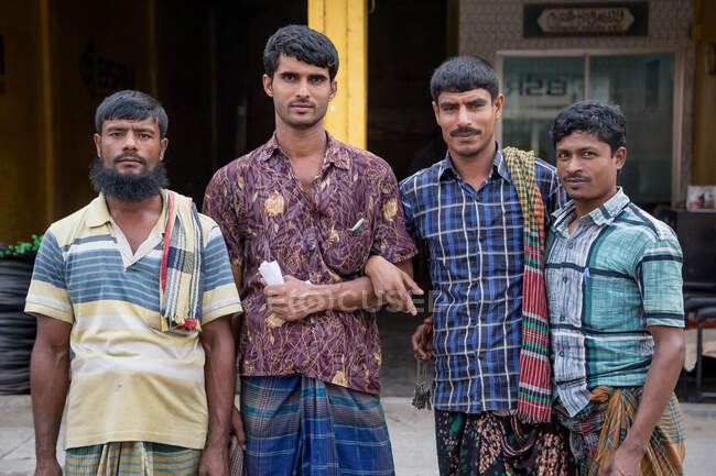 INDIEN, BANGLADESCHEN - 6. DEZEMBER 2015: Eine Gruppe indischer Männer in traditioneller Kleidung steht auf der Straße und blickt in die Kamera — Stockfoto