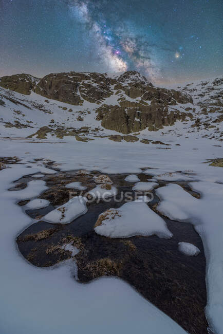 Paesaggio di pozzanghera di acqua ghiacciata vicino alla montagna sotto il cielo stellato notturno con Via Lattea — Foto stock