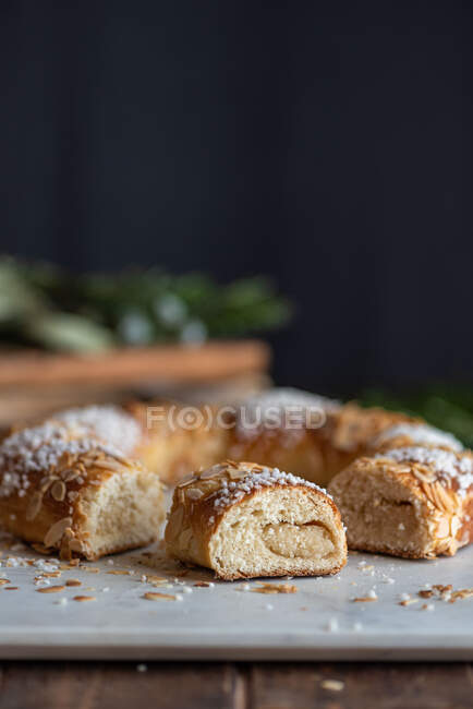 Delicious three kings cake pieces with coconut flakes and almond petals during Epiphany holiday on dark background — Stock Photo