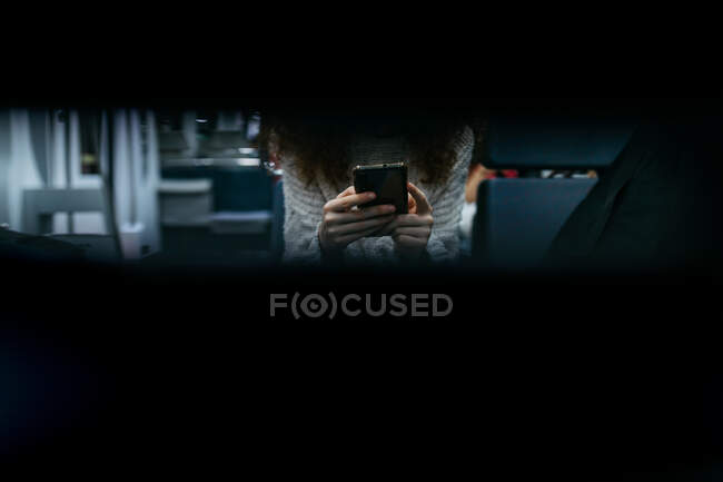 Через отверстие в виде урожая анонимный пользователь просматривает интернет на мобильном телефоне во время поездки в поезде — стоковое фото