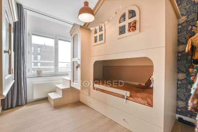 Gemütliches Bett in Form eines Hauses im hellen Kinderzimmer in der Wohnung tagsüber platziert — Stockfoto