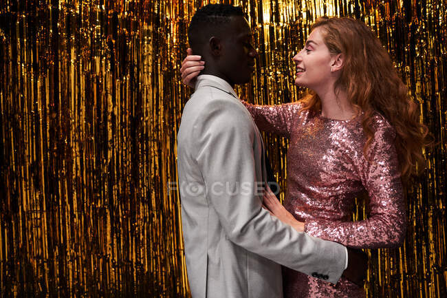 Side view of young romantic multiracial couple in stylish apparel embracing while celebrating New Years Eve — Stock Photo