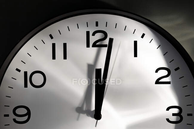 Reloj minimalista de forma redonda con números y flechas sobre fondo negro - foto de stock