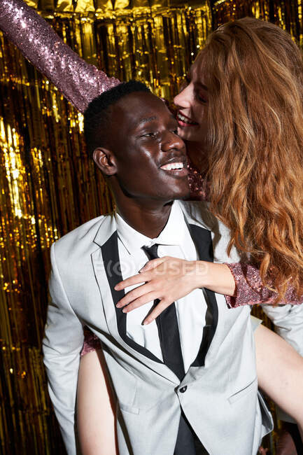 Allegro maschio afroamericano in giacca e cravatta che dà femminile amato cavalcata mentre celebra Capodanno — Foto stock