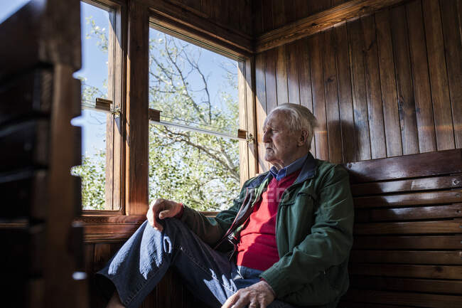 Uomo attraente e vecchio che viaggiano in una vecchia carrozza di legno che guarda fuori dalla finestra — Foto stock