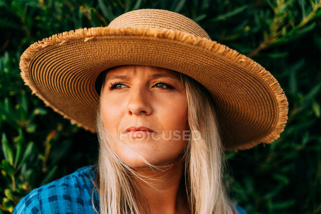 Schnodderige erwachsene Touristin mit Hut schaut weg vom Busch in Saint Jean de Luz Frankreich — Stockfoto