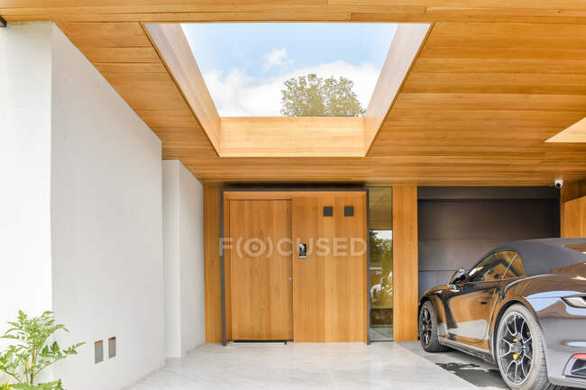 Modern sport car parked in backyard of stylish minimalist villa decorated with blooming plants on sunny day — Stock Photo