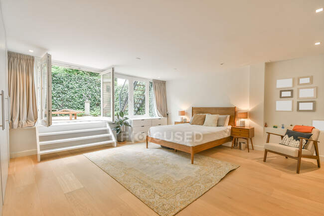Interior de la luz amplio dormitorio acogedora cama y entrada en la terraza en la casa de campo moderna - foto de stock