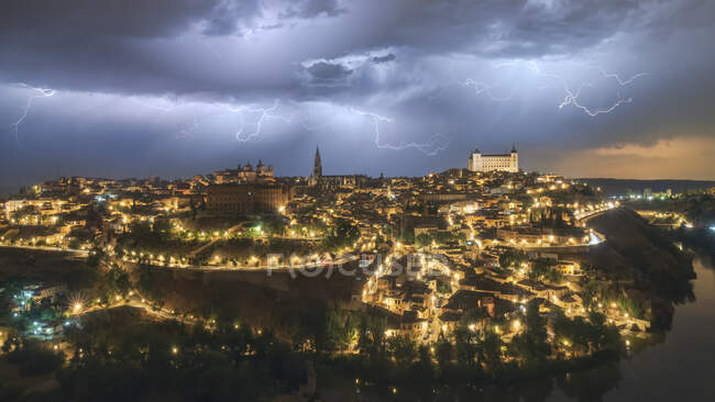 Stadtbild mit betagter berühmter Burg Alcazar von Toledo in Spanien unter bewölktem Himmel in der Nacht während eines Gewitters — Stockfoto