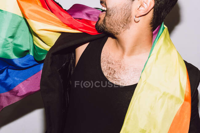 Crop unrecognizable excited bearded male laughing with mouth opened and waving multicolored flag symbol of LGBTQ pride — Stock Photo