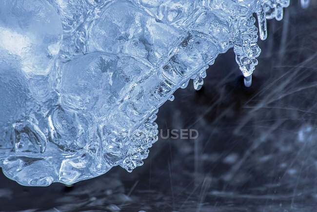 Textur aus kaltem, ungleichmäßigem, klarem Eis über dem in der Winternatur fließenden Wasserstrom — Stockfoto