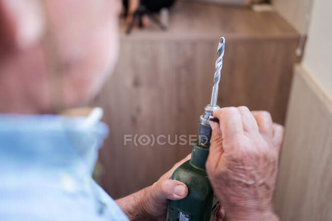 Cortar irreconhecível idade macho preparando chave de fenda de energia com bocal enquanto trabalhava na sala da casa de luz — Fotografia de Stock