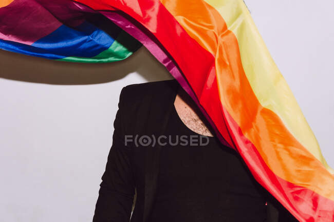 Unerkennbarer homosexueller Mann mit Versteck hinter Regenbogenfahne Symbol der LGBT-Gemeinschaft vor weißem Hintergrund — Stockfoto