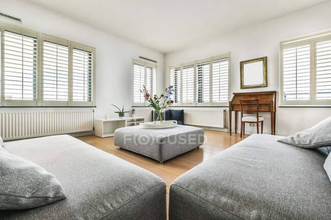 Современный интерьер комнаты с диванами и столом против окна дома при дневном свете — стоковое фото