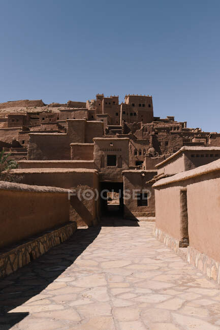 Старая каменная крепость против черепичной дорожки с тенью под голубым небом в Королевстве Марокко Северная Африка — стоковое фото