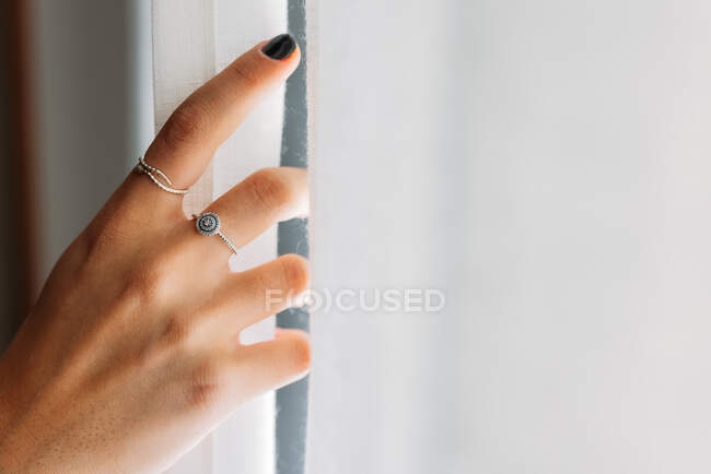 Vista close-up da mão mulher anônima com anéis abrindo as cortinas — Fotografia de Stock