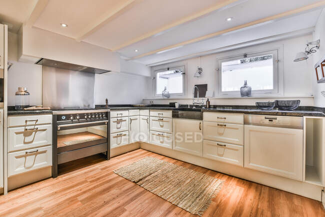 Сучасний інтер'єр просторої кухні з дерев'яною підлогою в новій квартирі — стокове фото
