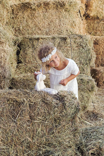Little girl with a stuffed animal in a haystack — Stock Photo