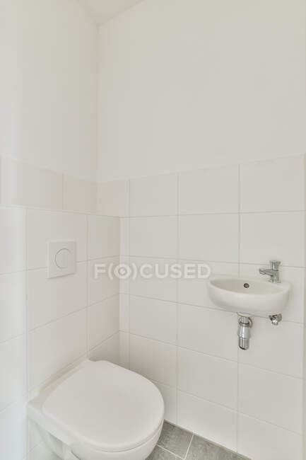 Interior de estilo minimalista baño moderno con inodoro limpio instalado en la pared de azulejos - foto de stock