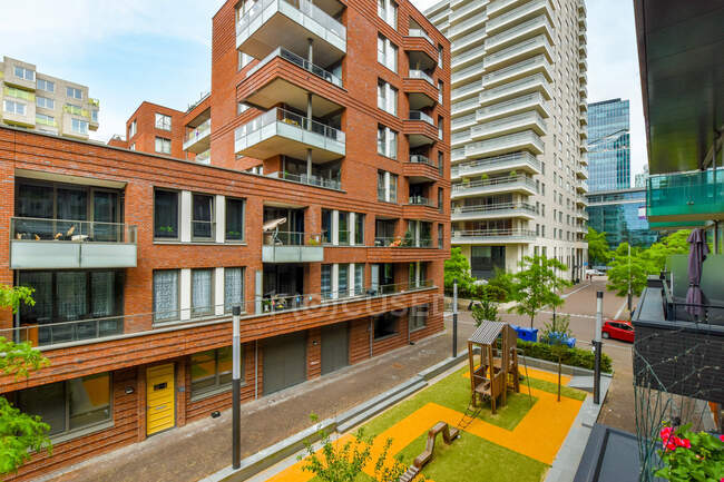 Asphaltierte Fahrbahn zwischen modernen mehrstöckigen Wohngebäuden und Spielplatz mit Rasenflächen in Amsterdam Niederlande — Stockfoto