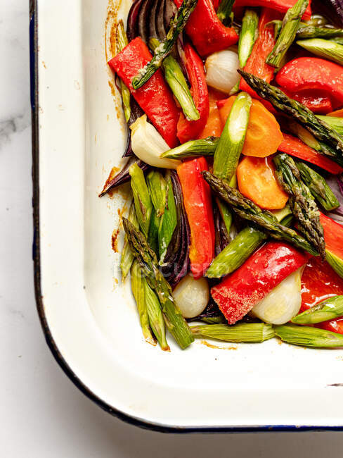 Вид сверху на вкусный свежий салат из различных овощей, подаваемый в металлической миске на мраморном столе — стоковое фото