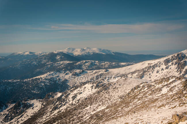 Paisagem pitoresca de pico de montanhas cobertas de neve localizada na Serra de Guadarrama, na Espanha, sob céu nublado à luz do dia — Fotografia de Stock