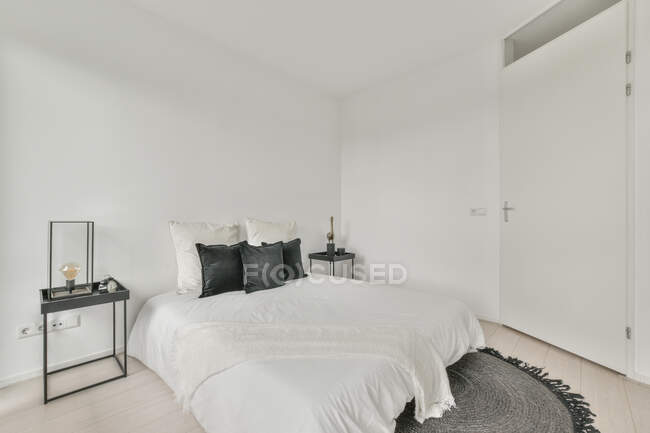 Интерьер просторной светлой спальни с удобной кроватью в современной квартире в дневное время — стоковое фото