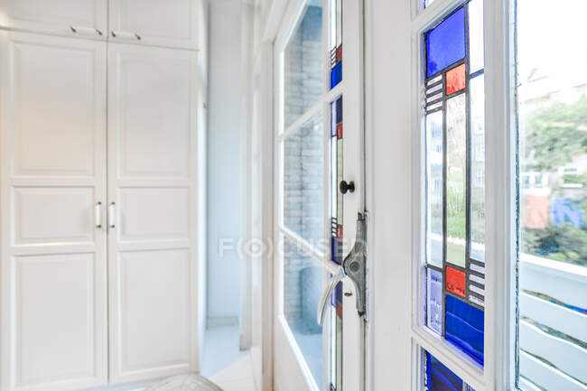 Vidro colorido da janela da varanda no apartamento moderno com mobiliário branco à luz do dia — Fotografia de Stock