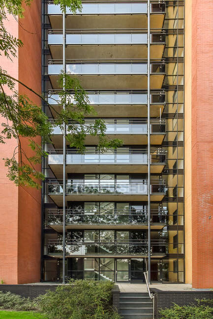 Maison haute contemporaine extérieure avec balcons clôturés et escalier contre les arbustes en journée en Hollande du Nord — Photo de stock