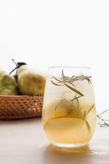 Холодний грушевий коктейль у склянці з розмарином та кубиками льоду, розміщеними на столі зі свіжими фруктами — стокове фото