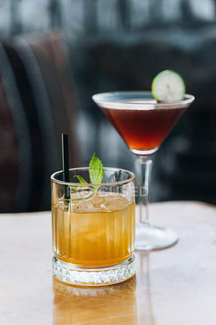 Kristallglas Whiskey-Cocktail mit Eiswürfeln und Minzblättern und Manhattan-Glas mit Limettenscheibe — Stockfoto