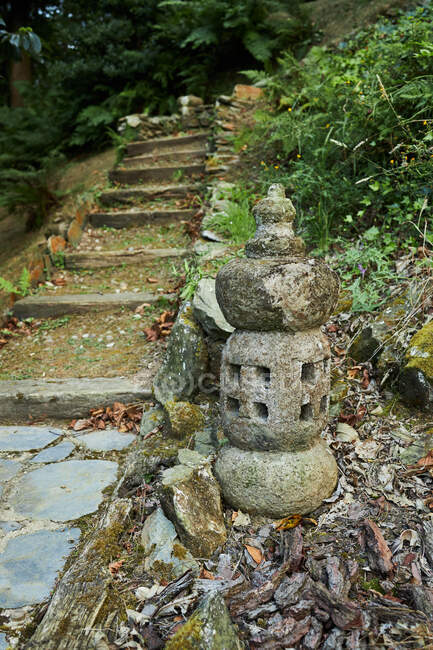Азійський ліхтар, виготовлений з необробленого каменю на території проти сходів і чагарників у парку Балі - Індонезія. — стокове фото