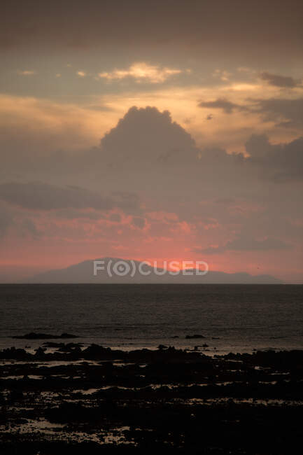 Paisagem de mar com colinas nebulosas no horizonte e praia coberta com algas marinhas sob céu nublado ao pôr-do-sol na Malásia — Fotografia de Stock