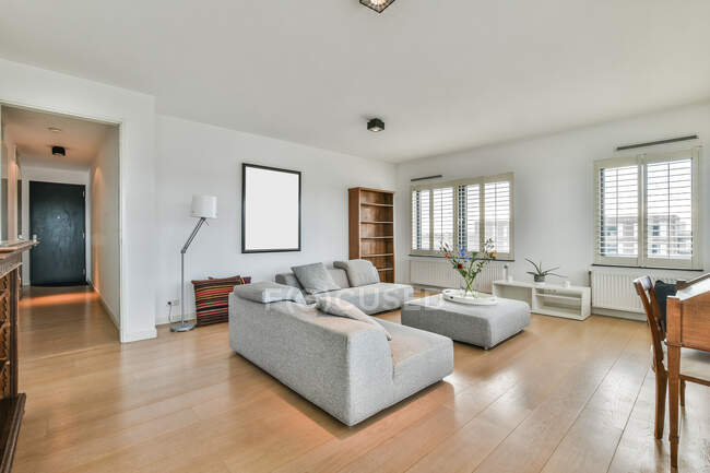 Quarto contemporâneo interior com sofás e mesa contra janelas e varanda vedada em casa à luz do dia — Fotografia de Stock