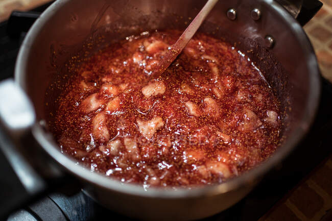 De dessus de la récolte personne anonyme agitant confiture de figue dans la cuisinière sur le poêle à la maison — Photo de stock