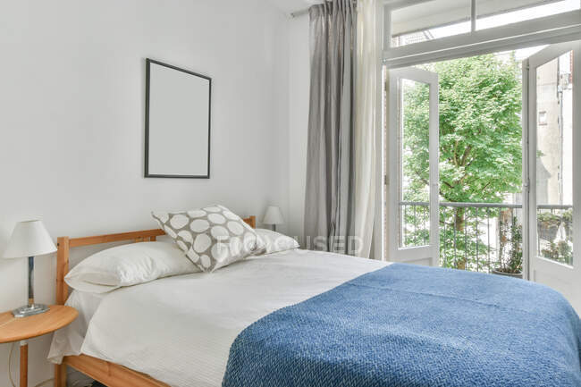 Interno di elegante camera da letto con comodo letto vicino alla finestra e pareti luminose durante il giorno — Foto stock