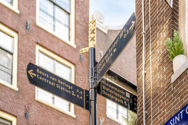 Angolo di guida basso con titoli e frecce tra gli esterni dell'edificio in mattoni invecchiati ad Amsterdam Olanda — Foto stock