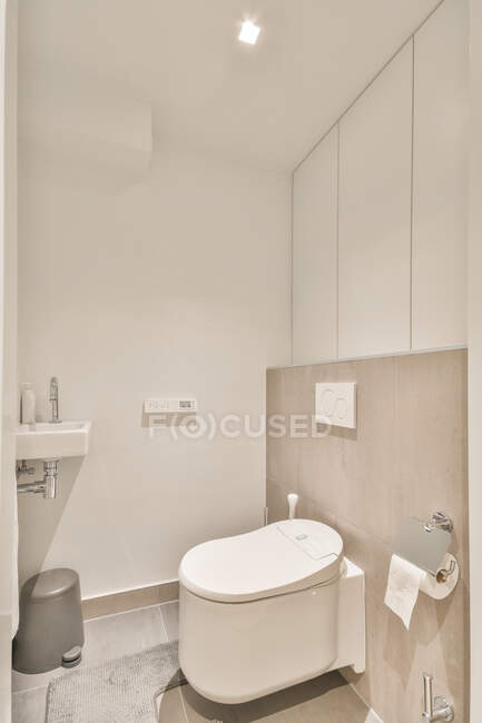 Интерьер современной ванной комнаты с белым туалетом и небольшой керамической раковиной в квартире — стоковое фото
