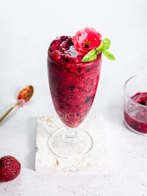 High angle of glass with sweet berry smoothie garnished with flower served on white background — Stock Photo