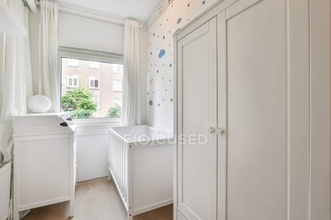 Kleine Holzwiege neben Fenster im Schlafzimmer mit minimalistischem Interieur tagsüber — Stockfoto