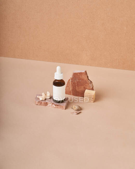 Petite bouteille d'huile de beauté et morceaux de savon naturel fait main avec pierre ponce sur fond deux couleurs — Photo de stock