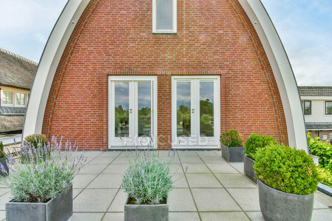 Креативный дизайн арочного фасада здания с черепичной крышей против растений под облачным небом в провинции Утрехт Холланд — стоковое фото