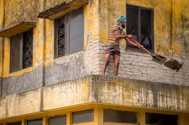 INDIA, BANGLADESH - DECEMBER 6, 2015: Side view of ethnic male in casual clothes standing on balcony and looking at camera — Stock Photo