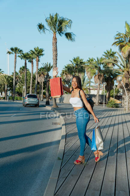 Веселий молодий афроамериканець з сумками для покупок викликає таксі на вулиці. — стокове фото