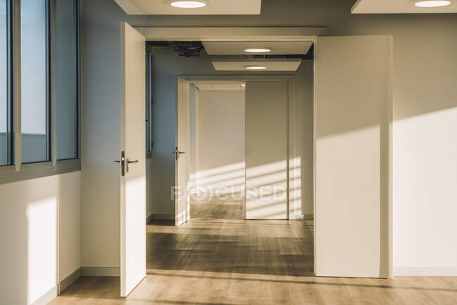 Інтер'єр порожнього просторого лофт-холу з геометричними тінями і сонячним світлом на білих стінах — стокове фото