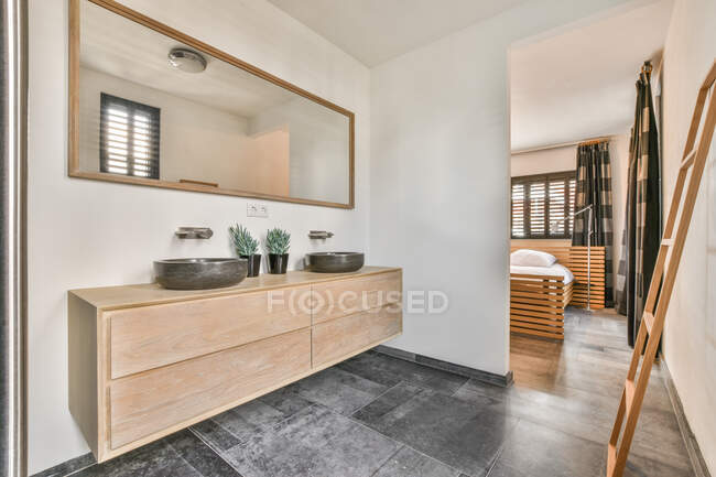 Keramische Waschbecken auf Holzschrank unter Spiegel hängen an Wand im Badezimmer — Stockfoto