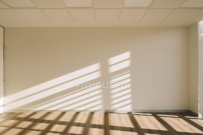 Interior do corredor espaçoso vazio do loft com sombras geométricas e luz solar nas paredes brancas — Fotografia de Stock