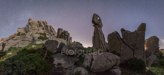 Pintoresco paisaje de formaciones rocosas ásperas en la cima de la montaña bajo el cielo estrellado por la noche - foto de stock